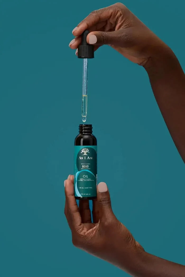 A person holding the dropper of As I Am Bond Oil, showcasing the lightweight and clear texture of the treatment oil.