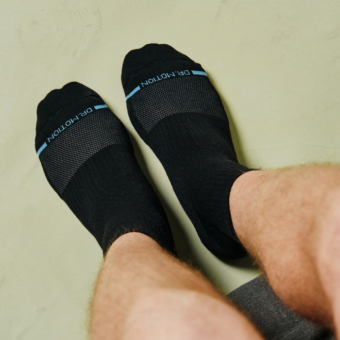 Black quarter compression socks with ribbed cuffs and blue stripes, worn on feet with visible legs.