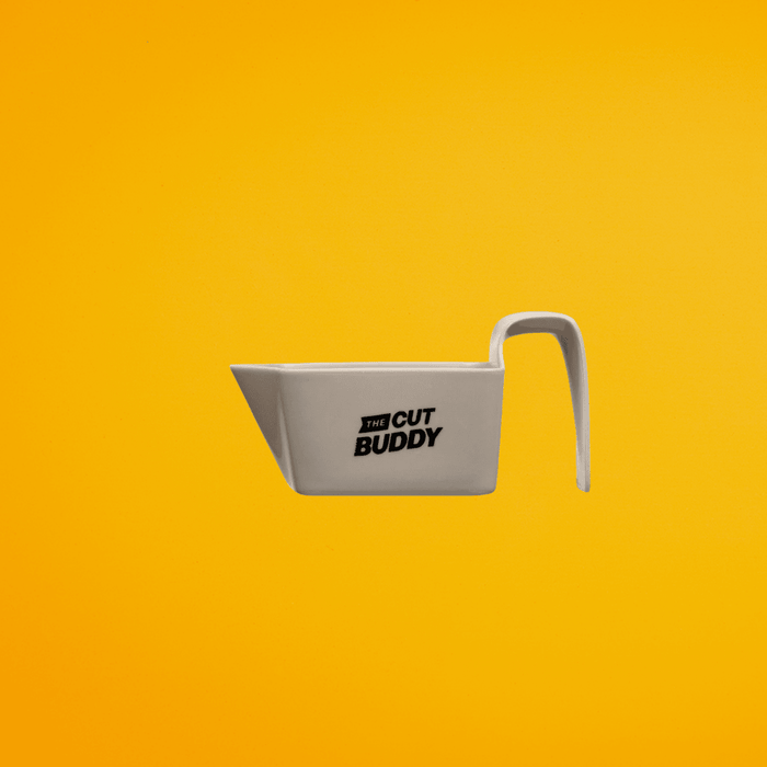 Grey Cut Buddy shaving accessory tool with a handle, designed for precision grooming, shown against a solid yellow background.