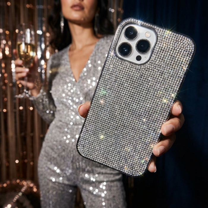 Woman in a sparkly outfit holds a drink, displaying a silver glitter Coconut Lane phone case to the camera.