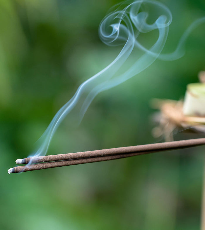 Burning incense stick with smoke curl