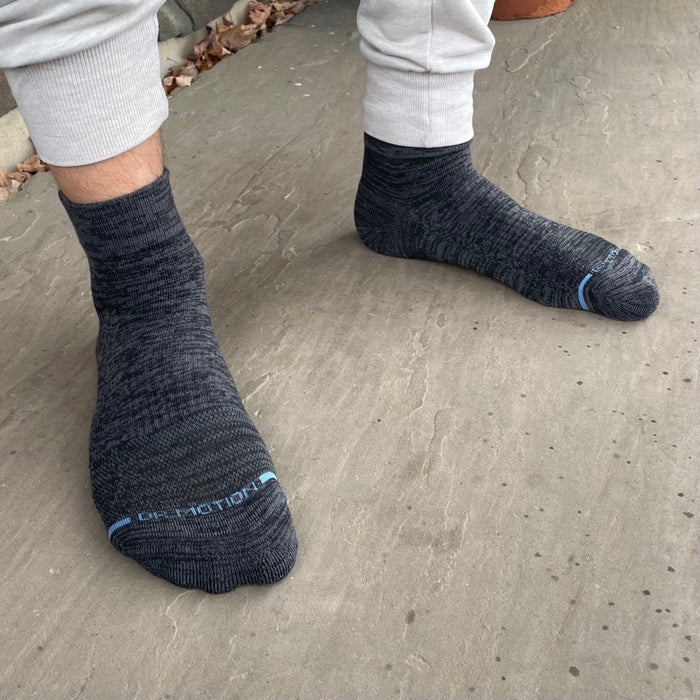 Quarter-length compression socks in dark gray with light blue accents, worn on feet.