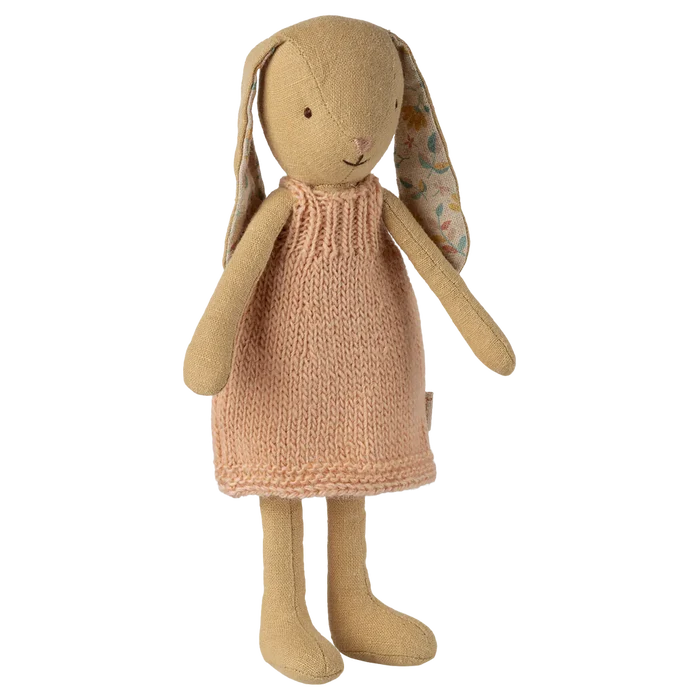 Stuffed bunny toy wearing a knitted dress on a white background