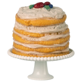 Layered cake with white frosting and fruit on top, placed on a white cake stand.