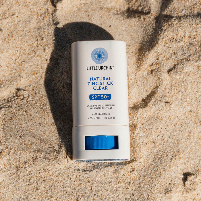 20g tube of Natural Zinc Stick SPF 50+, a clear, hydrating, vegan formula that provides UVA and UVB broad-spectrum protection from the sun while also being 4 hours water-resistant, styled with seashells against a yellow background. Packaged in a cream tube with minimal blue and black text on the label.