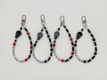 Four black beaded keychain wrist straps with skull beads and letter beads reading DEAD INSIDE, NOT A PHASE, EMO4EVA, and IM NOT OK.