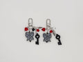 Two silver charm keychains featuring checkered bow, heart key, spike, star, and red heart charms