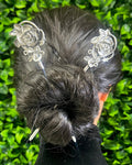 Model wearing silver rose hair sticks securing a bun hairstyle, elegant floral metal hair accessories for weddings, festivals, Renaissance fairs, and everyday wear.