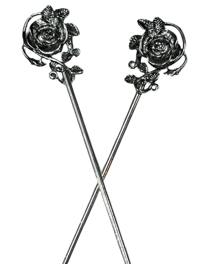 Pair of silver rose hair sticks with floral vine design, decorative metal hair pins crossed on a white background for buns, updos, and elegant hairstyles.