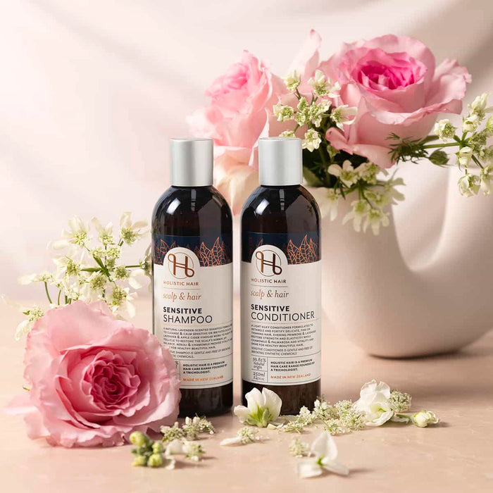 Two bottles of sensitive shampoo and conditioner with pink roses and flowers on a light background.