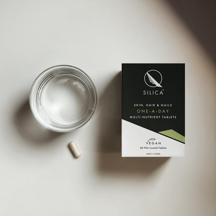 Qsilica supplement box with a pill and glass on a light surface.