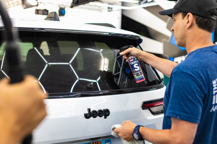 Person spraying P&S Triple S onto the back window of a car.