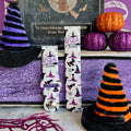Two Witch Please Fitbit Versa 1/2 band straps standing between a purple glitter witch hat and an orange striped hat prop.