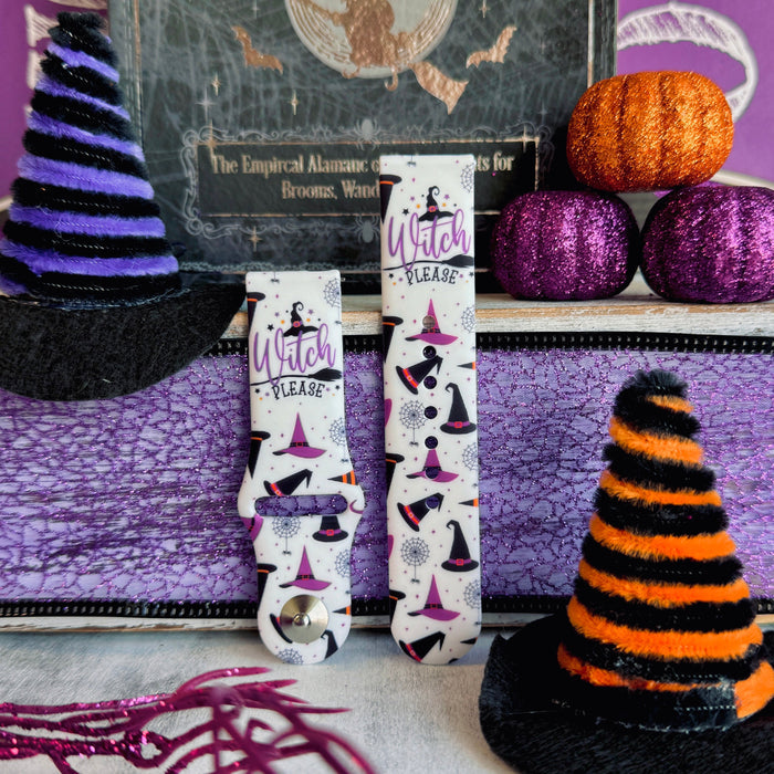 Two Witch Please Fitbit Versa 1/2 band straps standing between a purple glitter witch hat and an orange striped hat prop.
